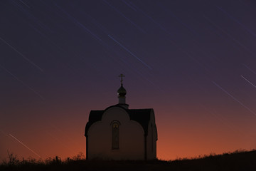 Traces of the stars in the night sky over the Orthodox church 