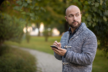 man with the gadget in hands in a park