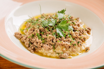 Oatmeal porridge with meat beef on wooden table