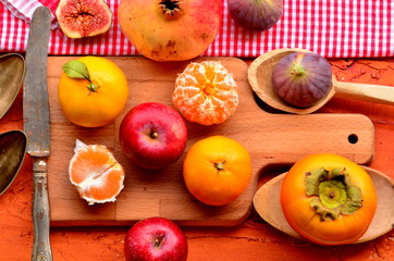 Naklejka na ściany i meble Figs, persimmon, pomegranate, avocado, apples and mandarines (tangerines) on rough background