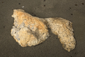 Tan granite boulder protrudes from the sand at Flagstaff Lake.