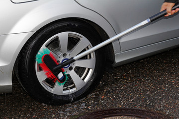 Ein Mann wäscht die Reifen seines Autos