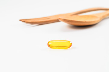 fish oil with wooden spoon and fork isolated white background