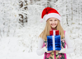 young girl with gift box in winter forest