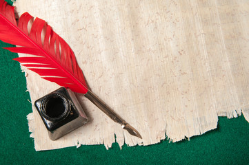 Red quill pen and black inkwell on a papyrus leaf