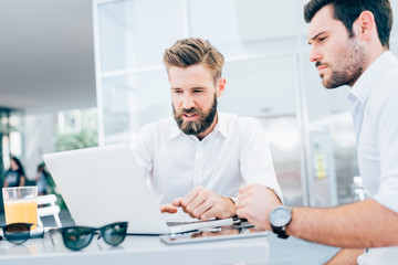 Obraz premium Two young modern businessman using laptop