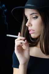 Portrait of the beautiful elegant girl smoking cigarette isolated on black