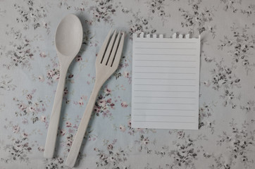 spoon, fork and empty paper on vintage style tablecloth