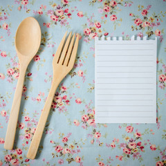 spoon, fork and empty paper on vintage style tablecloth