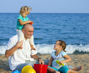 Fototapeta premium Dad and daughters on beach.