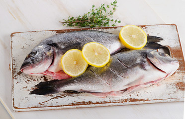 Fresh raw dorado fish on a wooden cutting board.