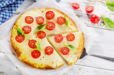 Italian Pizza Margherita with cheese and tomatoes on a wooden bo
