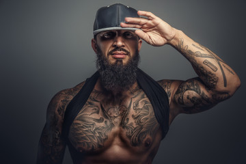 Brutal tattooed man in black cap.