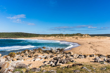 Fototapeta na wymiar Picturesque secluded Australian ocean beach with rocky shore