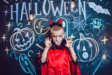 Boy in a Dracula costume posing on the background of the inscription Halloween