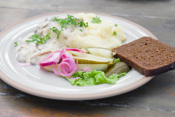 Mashed potatoes with creamy mushroom sauce and pickled cucumber