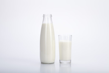 Glass bottle and a glass of milk nearby. White background