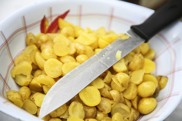 Bowl of ollucos cut in halfs with knife lying on top, preparing