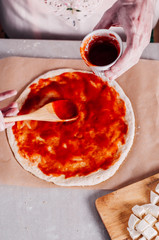 Spreading tomato sauce over pizza dough