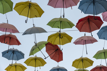 Fototapeta na wymiar Hanging Multicoloured umbrellas over blue sky Colourful umbrellas urban street decoration