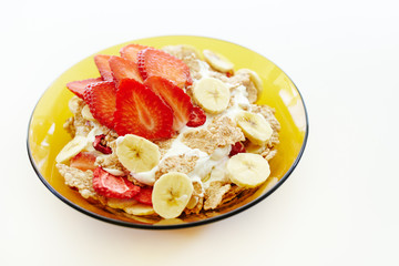 Bowl of banana and strawberries with yogurt and cereal breakfast isolated on white