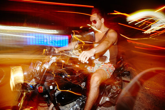 Riding Motorcycle On Night Streets Without Helmet . Long Exposure. High Speed Driving. Side View.