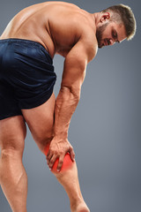 Fototapeta na wymiar Muscle man having calf pain. Bodybuilder tension. Glowing red spot concept