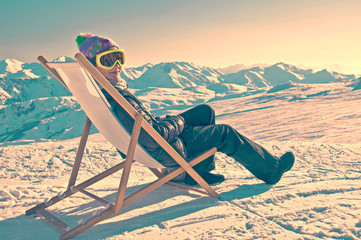 Girl sunbathing in a deckchair on the side of a ski slope in the Alps, France