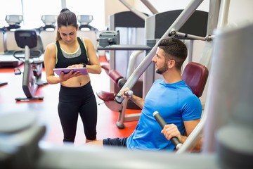 Fototapeta premium Trainer working with athlete at weights machine