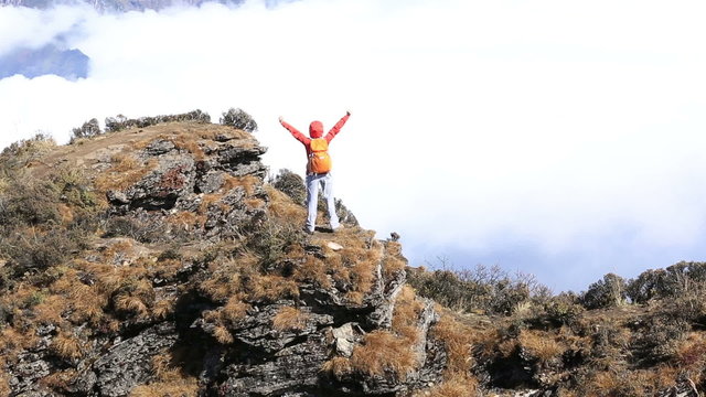 cheering young woman hiker open arms to beautiful landscape on mountain peak