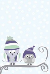 Two little owls sitting with winter hats on a tree branch and snowy background 