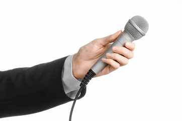 Business and speech topic: Man in black suit holding a gray microphone on an isolated white background in studio