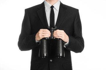 Business and search topic: Man in black suit holding a black binoculars in hand on white isolated...