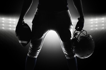 Silhouette of sportsman holding ball and helmet