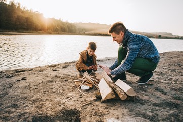 father and son burning fires on the lake