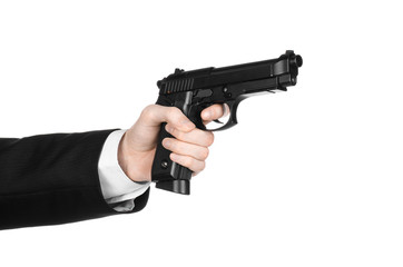Firearms and security topic: a man in a black suit holding a gun on an isolated white background in...