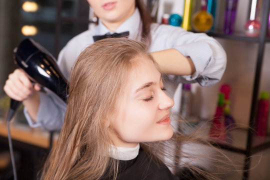 Hairstylist Drying Hair Blonde in Salon 