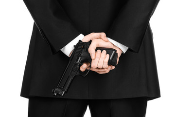Firearms and security topic: a man in a black suit holding a gun on an isolated white background in...