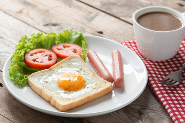 Fried toast with egg, sausage and a cup coffee.