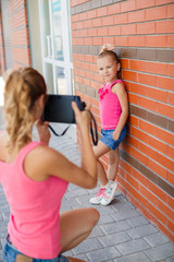 Mom photographs her daughter on the street in the city