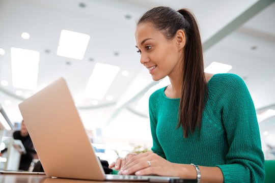 Happy Female Student Using Laptop In University