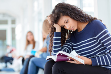 Woman reading book in university hall