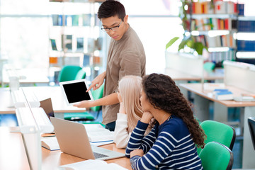 Student showing something on tablet computer to his classmates