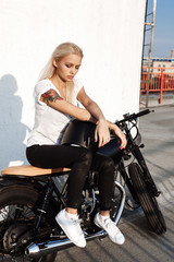 Naklejka na ściany i meble Biker girl sitting on vintage custom motorcycle