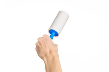 Clean clothes and cleaning the house topic: human hand holding a blue sticky brush for cleaning clothes and furniture from dust isolated on white background in studio.