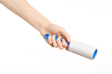 Clean clothes and cleaning the house topic: human hand holding a blue sticky brush for cleaning clothes and furniture from dust isolated on white background in studio.