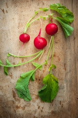 Radishes with radishes leaves on rustic wooden board (top view)