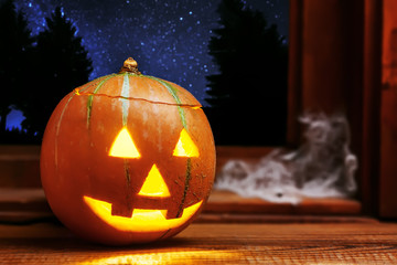 Halloween pumpkin head jack o lantern near window, night sky full of stars on background