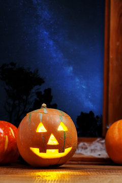 Halloween Jack O Lantern pumpkin indoor, night sky full of stars outside
