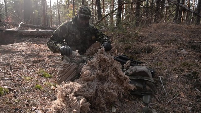 Sniper in forest/Sniper preparing his camouflage suit in the woods